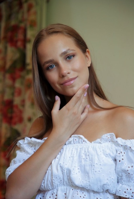 Nice teen Cassia flips thru a book before posing naked on a chesterfield