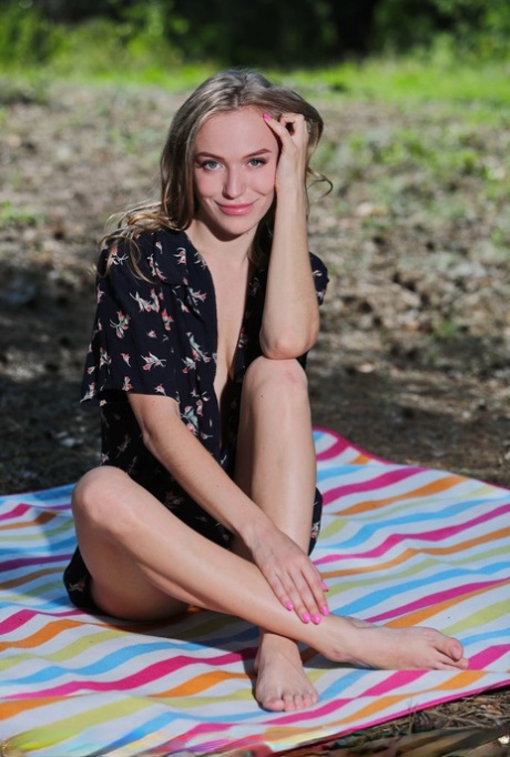 Beautiful teen Aislin gets totally naked on a towel spread out on a field