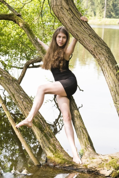 Barefoot teen Londa removes a black dress to pose nude in a tree