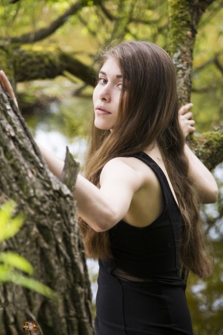Barefoot teen Londa removes a black dress to pose nude in a tree